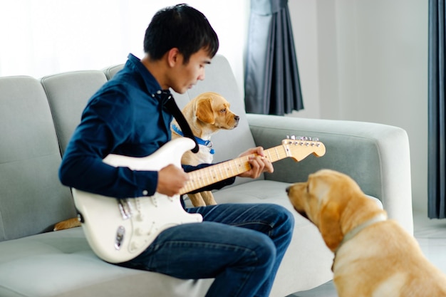 Guitariste jouant de la guitare sur un canapé à la maison Pratiquer la guitare à la maison Détendez-vous en jouant des instruments à cordes