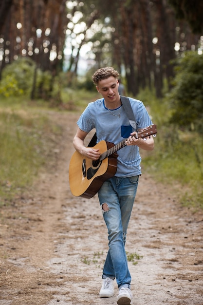 Guitariste de marche jouant le concept de randonnée en forêt.