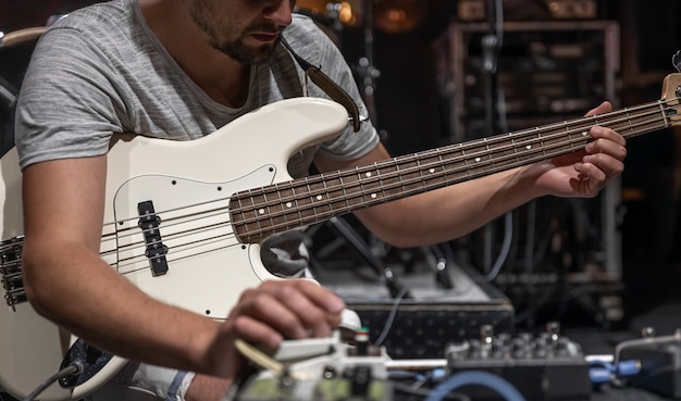 Un guitariste masculin mettant en place des effets de traitement audio de guitare sur scène.