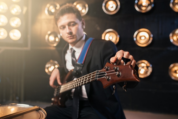 Guitariste de rock en costume jouant à la bas-guitare, scène avec lumières