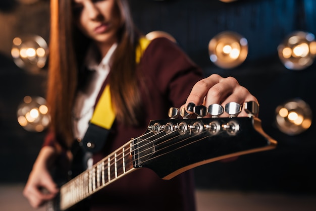 Photo guitariste rock féminin en costume syntonise la guitare