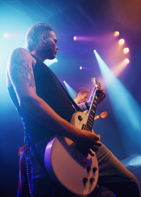 Guitarre de musique et d'éclairage avec un homme sur scène pour un spectacle de concert ou une représentation lors d'un festival de dessous Évènement de fête ou de divertissement et musicien ou guitariste jouant d'un instrument lors d'une production musicale