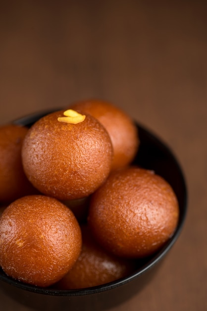 Gulab Jamun dans un bol sur fond de bois.