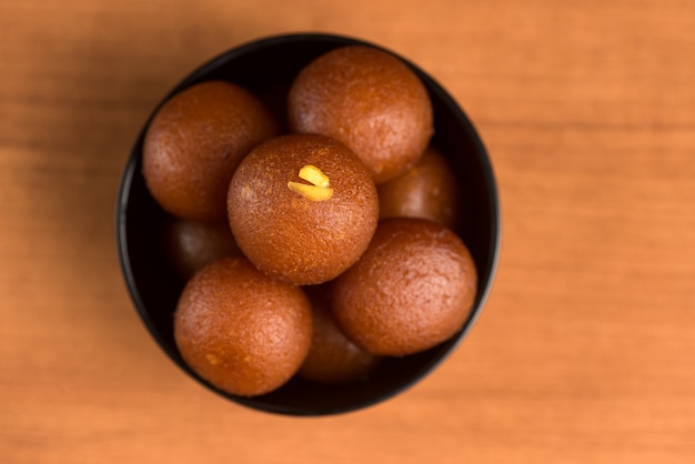 Gulab Jamun dans un bol sur fond de bois.