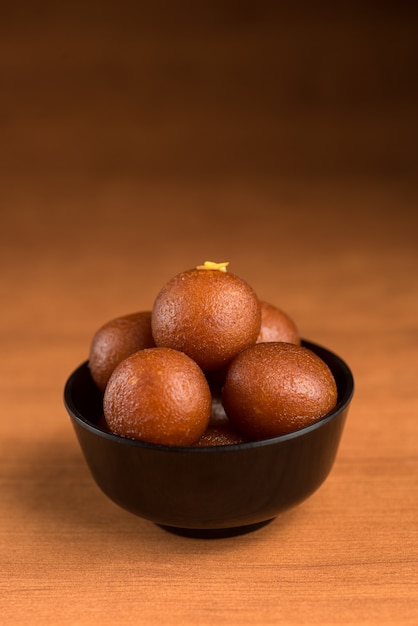 Gulab Jamun dans un bol sur fond de bois.