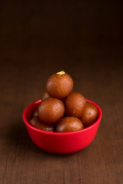 Gulab Jamun dans un bol rouge sur bois. Dessert indien ou plat sucré.