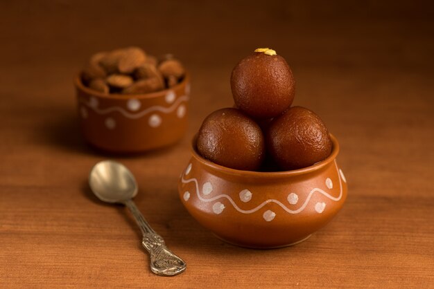 Gulab Jamun en pot d'argile avec cuillère et fruits secs. Dessert indien ou plat sucré