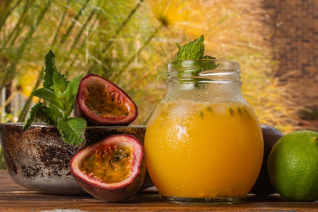 Gulupa ou jus de fruit de la passion entouré d'écorces et de fruits entiers et coupés citrons et menthe verte