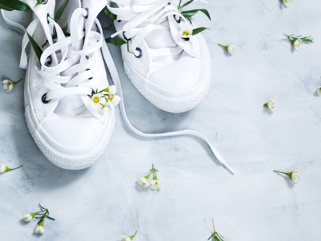 Gumshoes blancs avec des fleurs fraîches sur fond gris