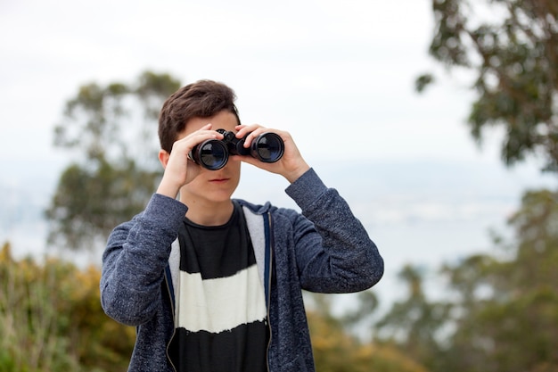 Guy adolescent regardant avec des jumelles