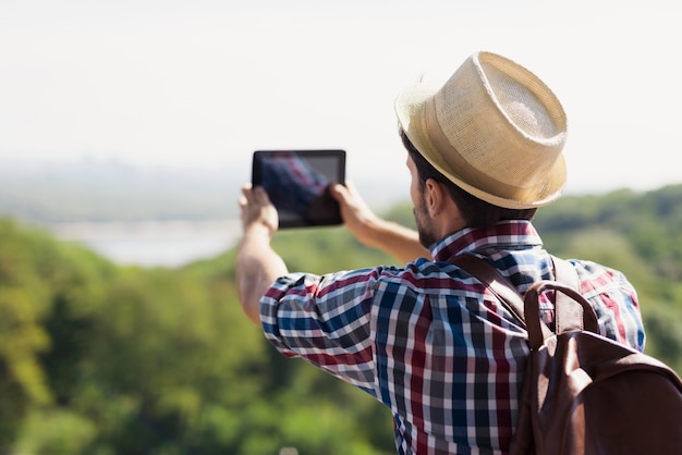 Guy au chapeau et avec sac à dos pour voyager fait de la phographie.