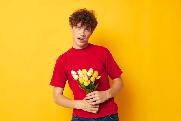 Guy aux cheveux bouclés rouge romantique posant avec un bouquet de fleurs jaune fond isolé inchangé