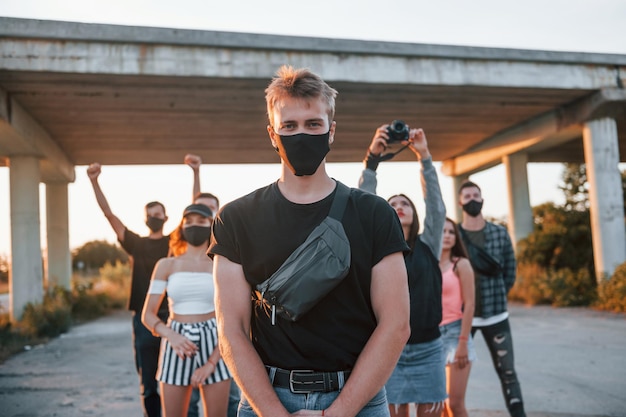 Photo guy à l'avant de la foule groupe de jeunes protestataires qui se tiennent ensemble militant pour les droits de l'homme ou contre le gouvernement