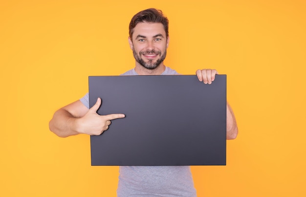 Guy avec bannière publicitaire vierge isolé sur fond de studio homme tenant une affiche vierge vide montrant une plaque