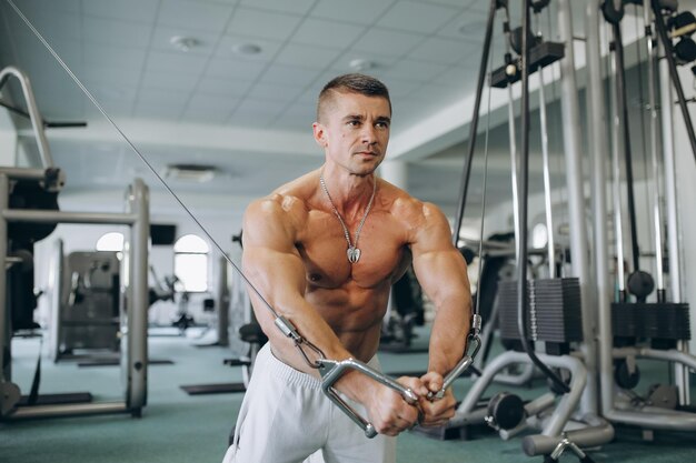 Guy bodybuilder exécuter l'exercice avec du poids dans la salle de gym