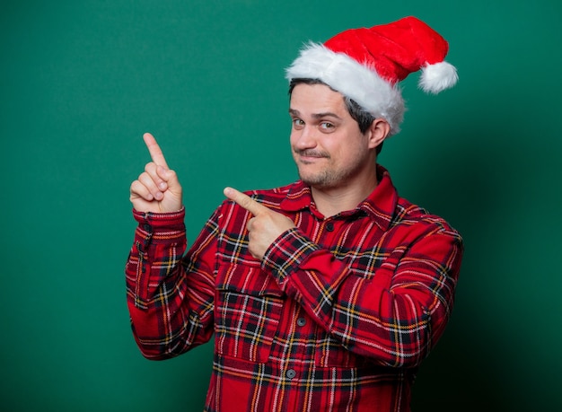 Guy en chapeau de Noël et chemise tartan sur vert