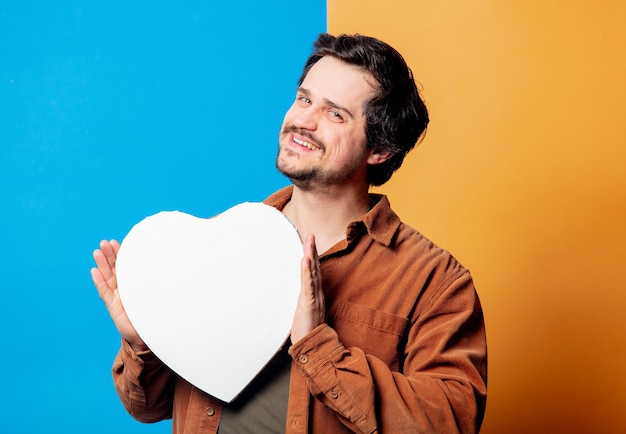 Guy en chemise tenir la bannière en forme de coeur sur fond jaune et bleu