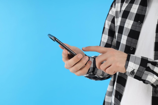 Guy en chemise tient le téléphone sur fond bleu