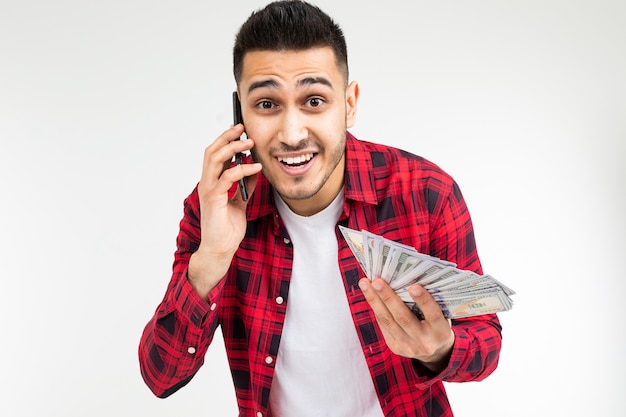 Guy dans une chemise à carreaux rapporte gagner de l'argent par téléphone sur un blanc avec copie espace
