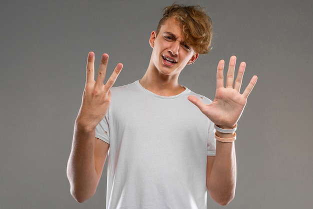 Guy dans un t-shirt gris montre le numéro huit avec ses doigts