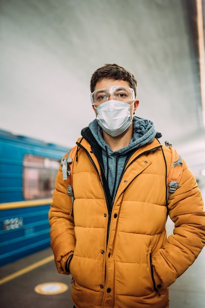 Guy debout à la station dans un masque de protection médicale sur son visage