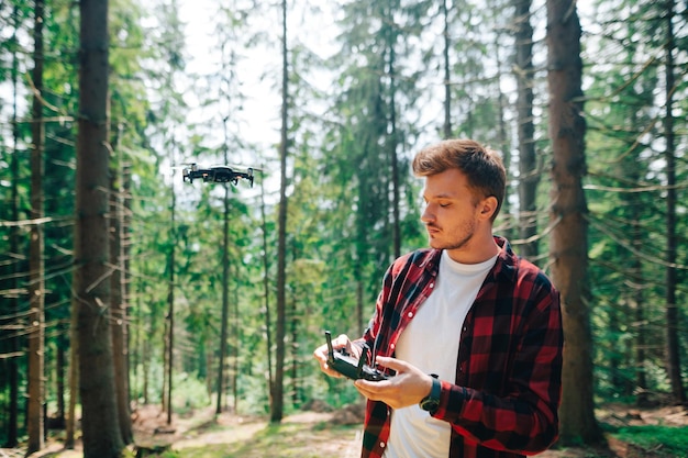 Guy fait voler un drone à travers la forêt dense et tire du contenu