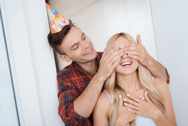 Guy fermé les yeux de la fille mains. Anniversaire fille sourit.