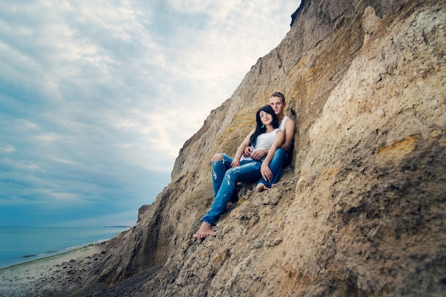 Guy et une fille en jeans et t-shirts blancs au bord de la mer