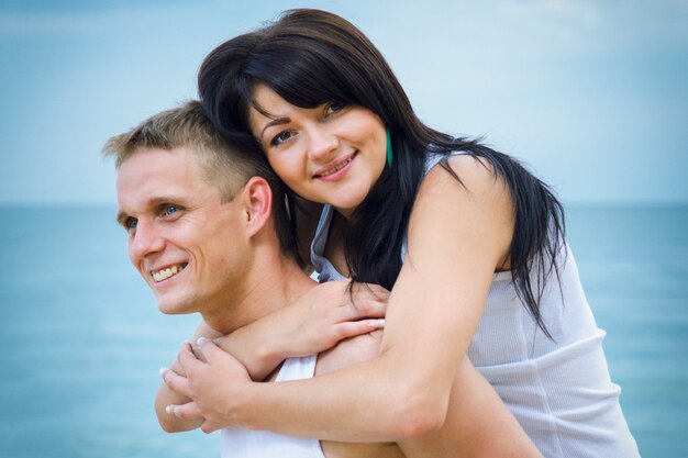 Guy et une fille en jeans et t-shirts blancs au bord de la mer