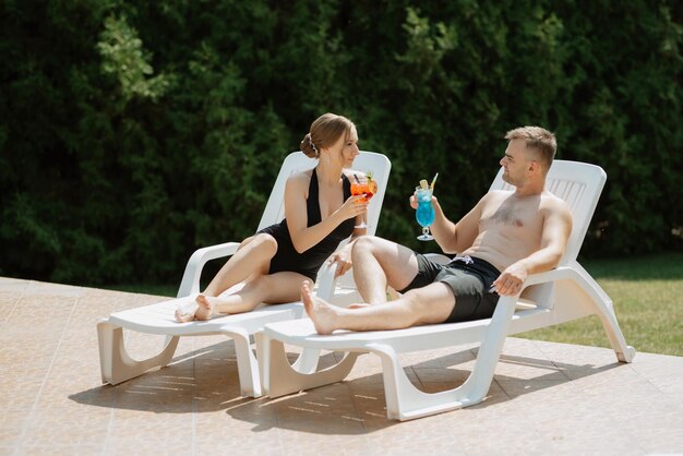 Guy et une fille en maillot de bain se détendent près de la piscine bleue