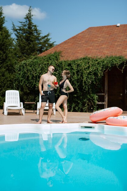 Guy et une fille en maillot de bain se détendent près de la piscine bleue