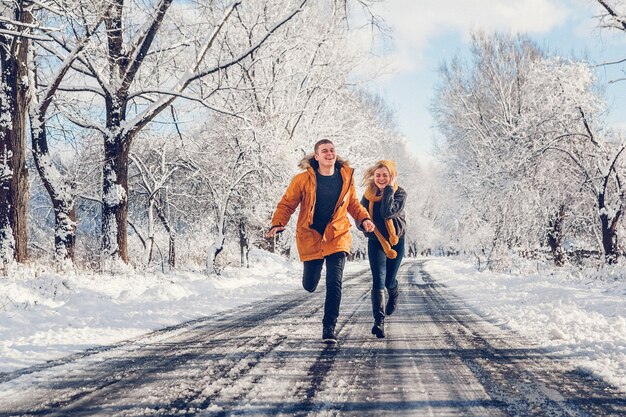 Guy et fille marchent et s'amusent dans la forêt en hiver.