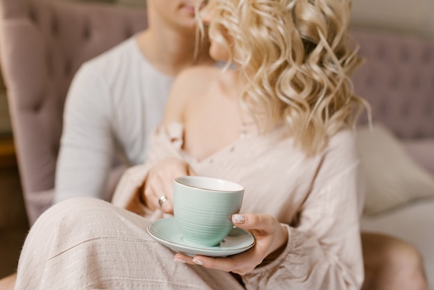 Guy et fille avec une tasse de café au lit, soft focus