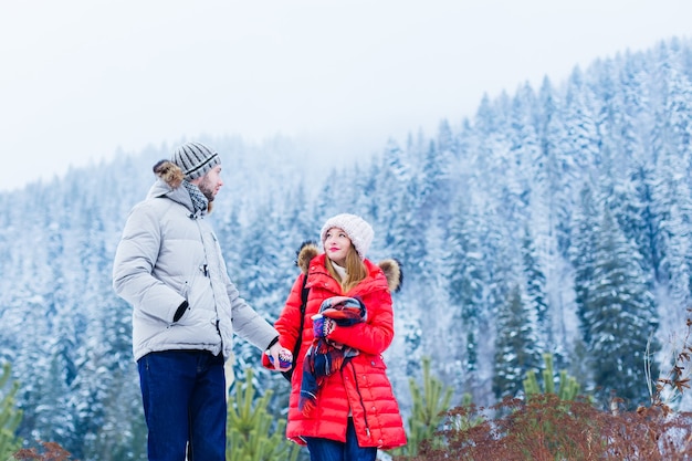 Guy et fille en vestes d'hiver et chapeaux se tiennent la main et se regardent