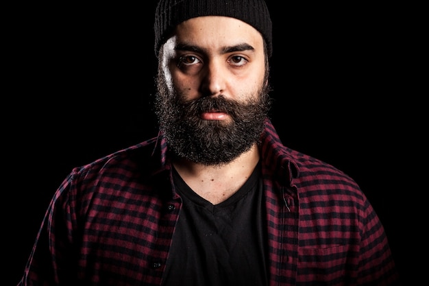 Guy hipster barbu en colère sur fond noir en photo studio