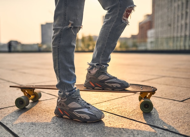 Guy de longboard dans la rue lors d'une belle soirée d'été. Tonifié dans des couleurs chaudes.