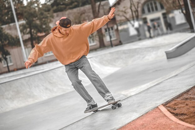 Guy avec les mains sur les côtés faisant du skateboard dans le skatepark