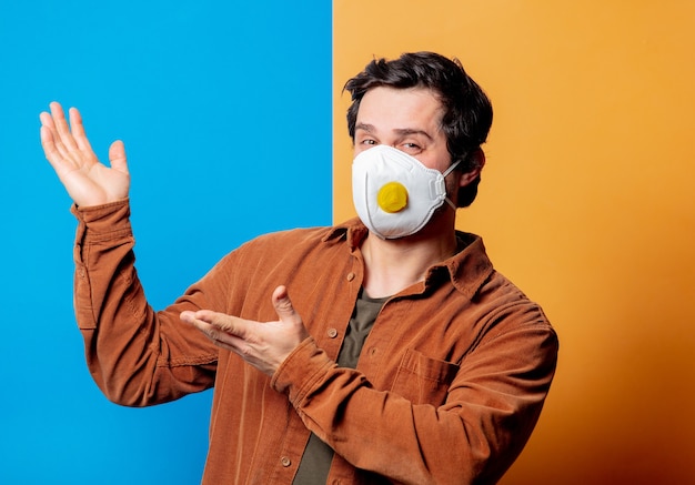 Guy en masque FFP2 de bonne humeur sur fond jaune et bleu