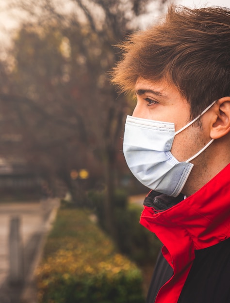 Guy en profil avec masque protecteur dans un parc un jour d'hiver