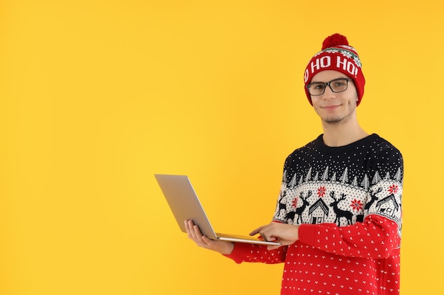 Guy en pull de Noël avec ordinateur portable sur fond jaune