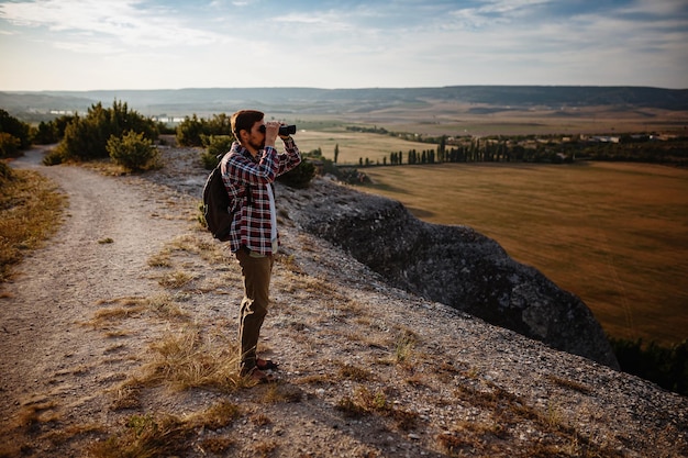 Guy regardant des jumelles dans l'homme de la colline en t-shirt avec sac à dos