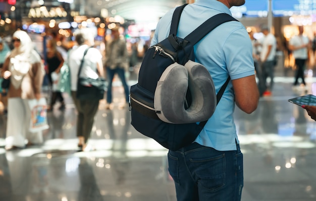 Guy avec sac à dos à l'aéroport près de l'horaire de vol à l'aéroport