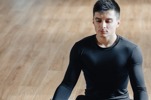 Guy sportif attrayant, faire du yoga. solarium et ombres. gymnase et sports.