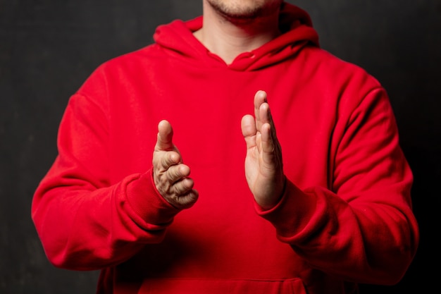 Guy en sweatshirt rouge applaudissements sur mur sombre