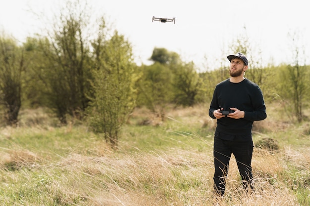 Photo guy en tenue noire complète avec télécommande et pilotant un drone avec fond de champ