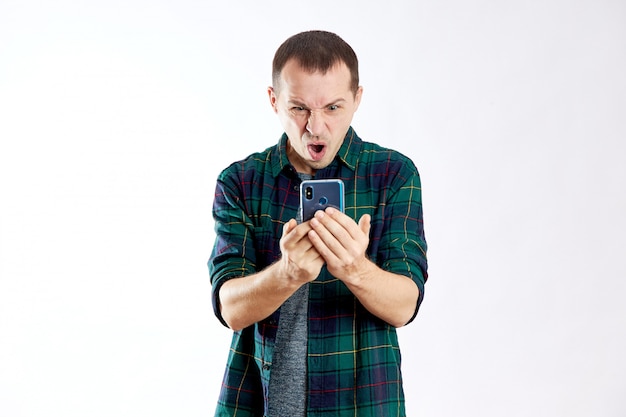 Guy tient le téléphone dans ses mains et le pointe du doigt. Un homme joue sur son téléphone et regarde des vidéos, les réseaux sociaux