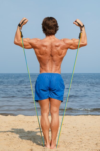 Guy travaillant avec élastique sur la plage