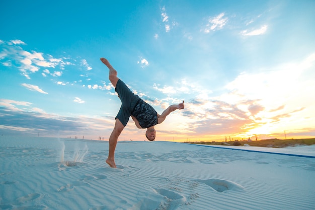 Guy vole à l'envers sur le sable dans le désert.