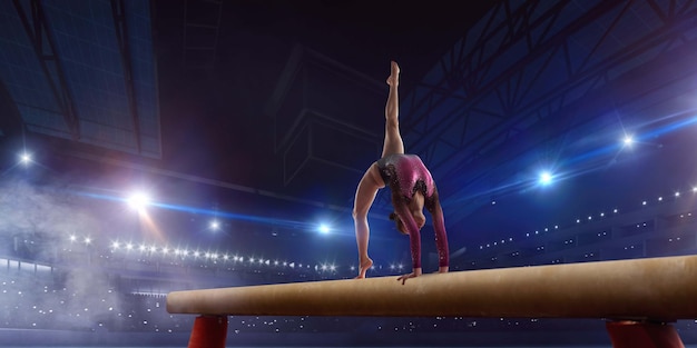 Gymnaste féminine faisant un tour compliqué sur la poutre d'équilibre de gymnastique dans une arène professionnelle