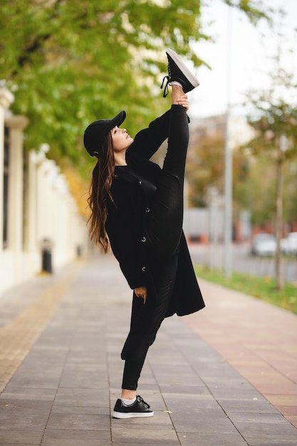 Gymnaste de fille avec une jambe levée au-dessus de sa tête sur une rue de ville